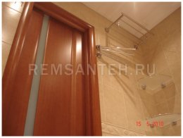 На фото ремонта ванной комнаты установка двери с доборами после укладки, затирки плитки на стены и пол в совмещённом санузле после монтажа подвесного реечного потолка вешаю полочки для ванной.